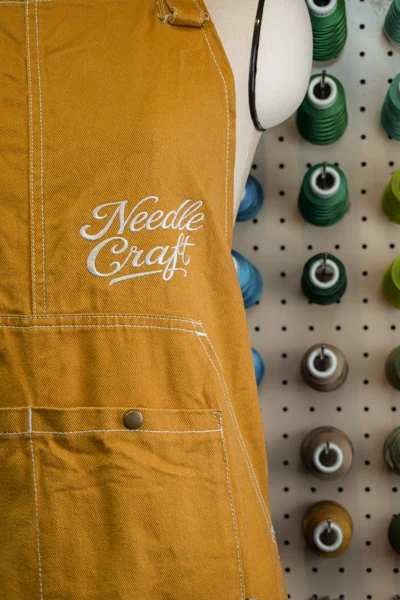 マスタード色の衣服に施した白いスクリプト刺繍