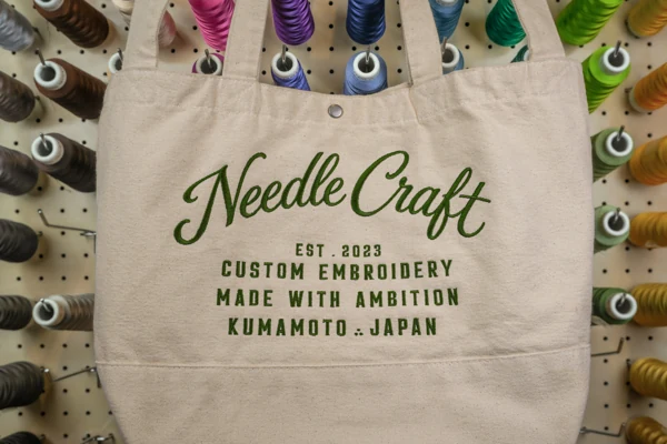生成りのバッグに緑糸で施したスクリプト刺繍