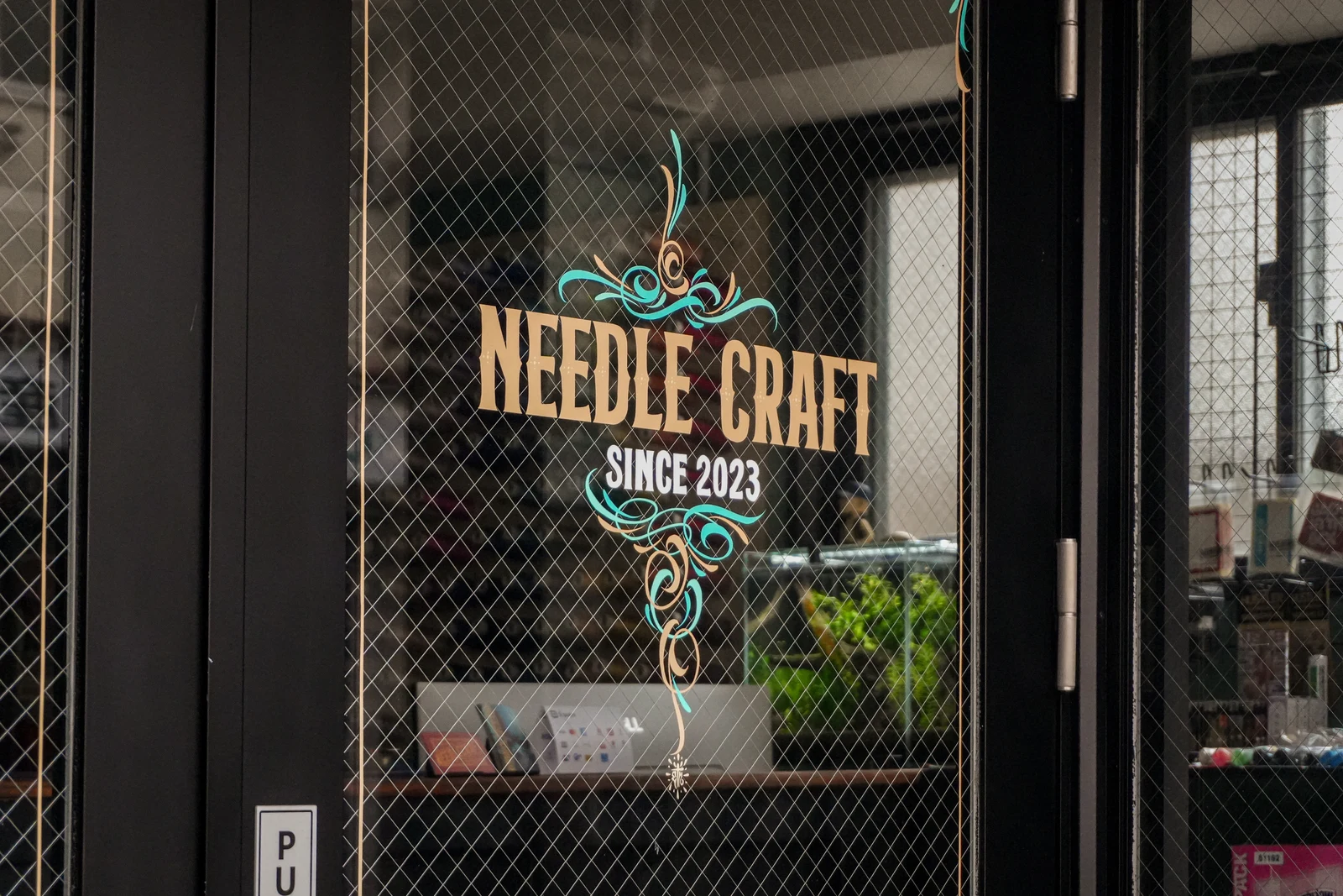 店舗ガラスに描かれたNEEDLE CRAFTのサインペイント