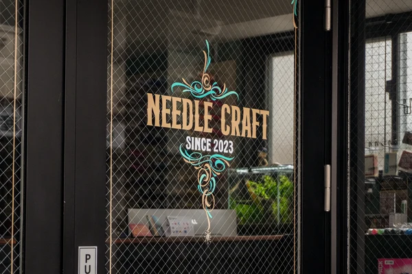 店舗ガラスに描かれたNEEDLE CRAFTのサインペイント
